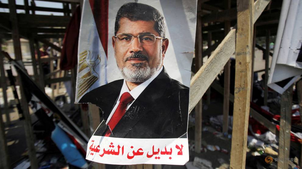 a-poster-of-egypt-s-president-mursi-is-seen-near-members-of-muslim-brotherhood-after-night-clashes-with-anti-mursi-in-giza-1.jpg