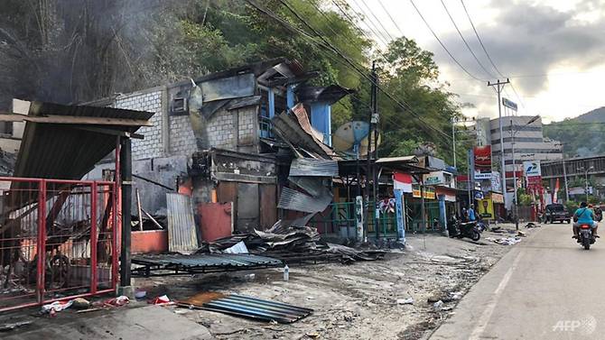 residents-ride-motorcycles-next-to-torched-shops-in-jayapura.jpg